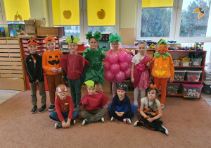 Dzieci przebrane za owoce i warzywa pozują do zdjęcia.