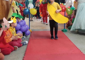 Chłopiec przebrany za banana idzie po czerwonym dywanie.