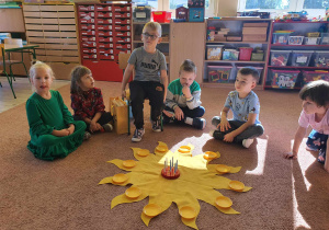 Dzieci świętują z jubilatem wokół słoneczka urodzinowego.