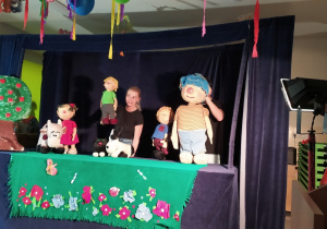 Aktorzy manipulują lalkami w teatrzyku.